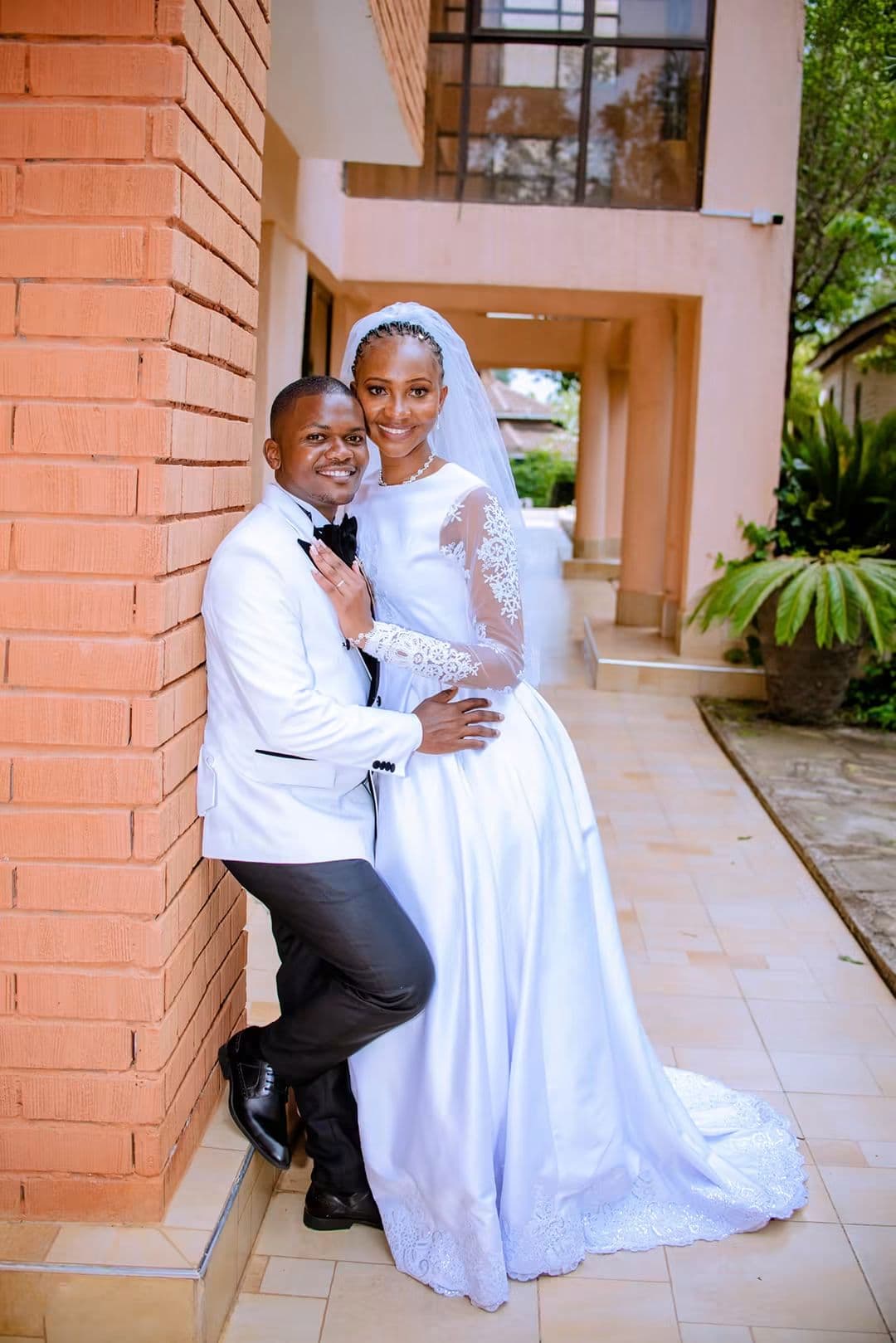 Bride and groom embracing against a brick wall
